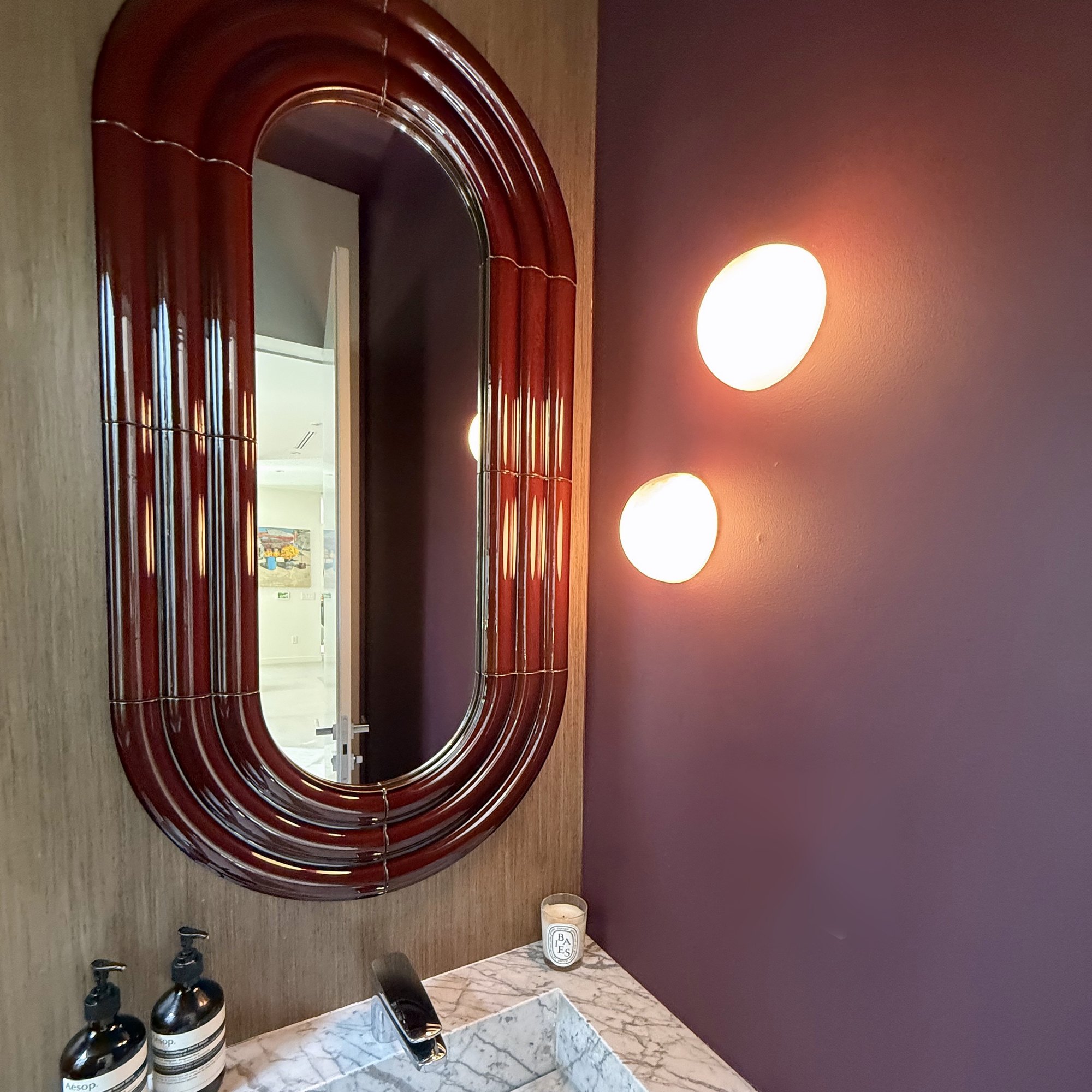 Powder room with lacquered mirror, plaster sconces and marble sink